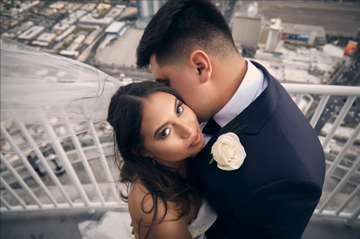 Groom kisses his bride's forehead on a rooftop overlooking Las Vegas